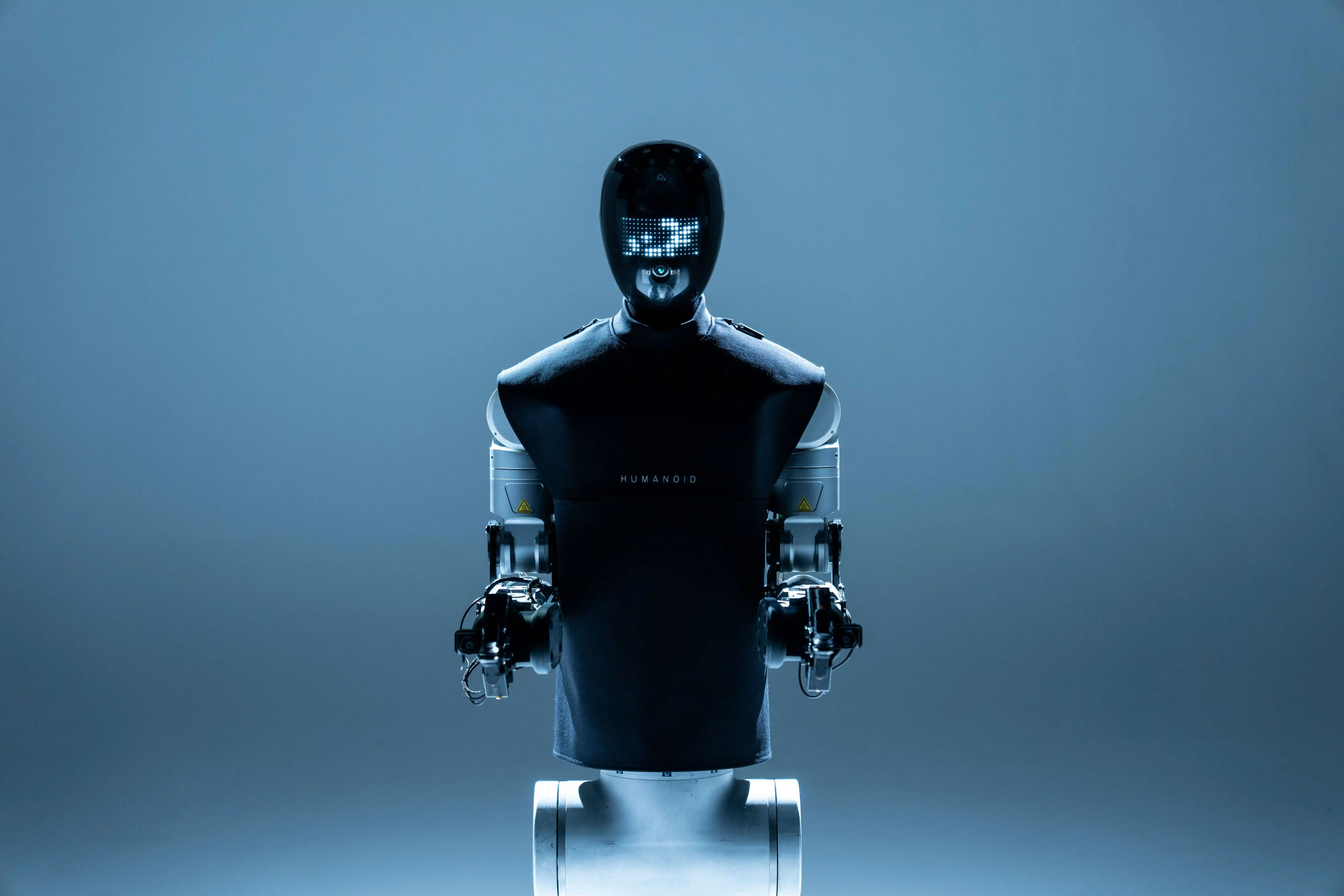 Humanoid robots working together at a row of workstations